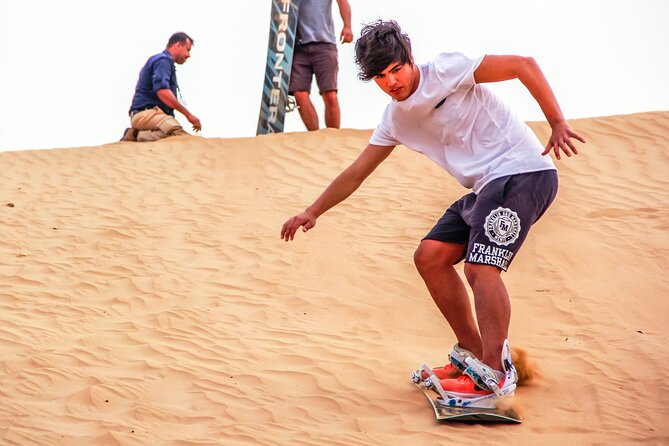 Dubai Private Sunset Desert Drive with Wildlife Experience - Learning to sandboard on soft orange dunes